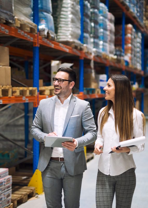 two,successful,business,people,walking,through,large,warehouse,center.,manager